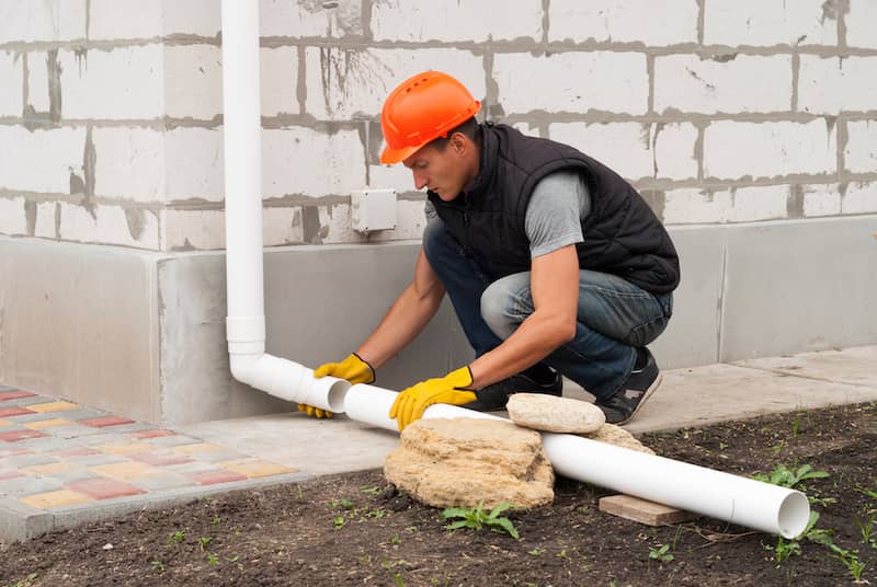 Man extending downspouts on gutters.