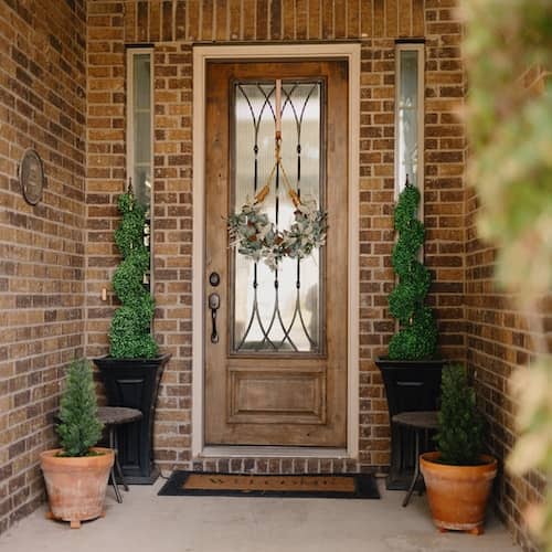 Front porch with plants in pots and welcome mat.