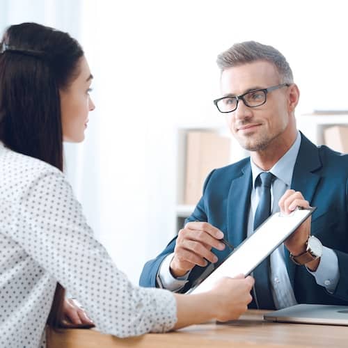 Two individuals discussing paperwork in an office setting.