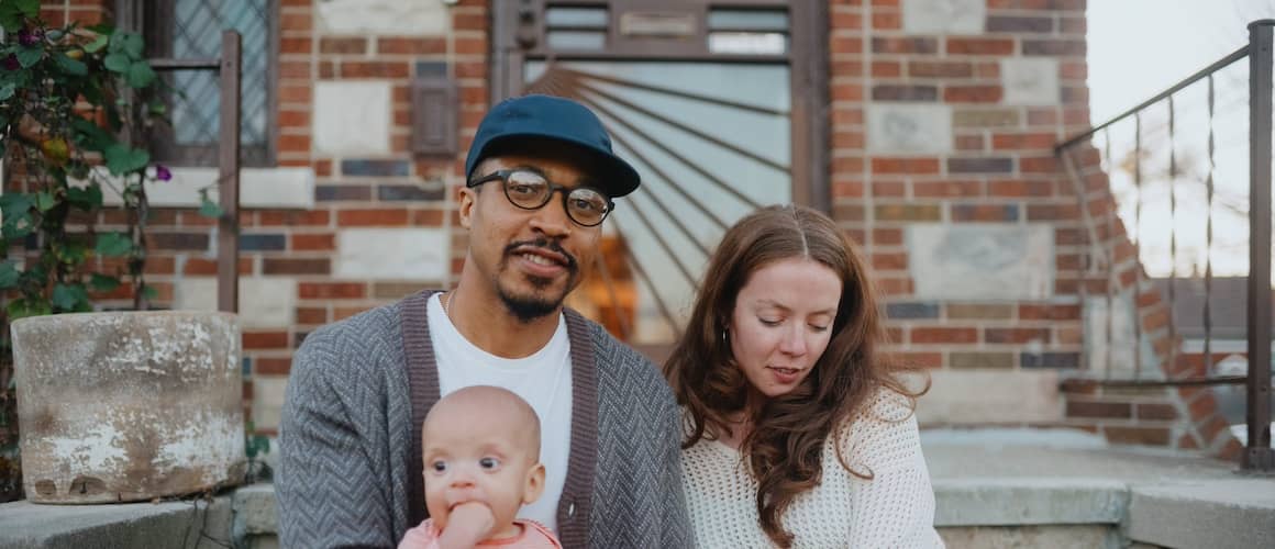 Couple with their young child on lap sitting on porch.