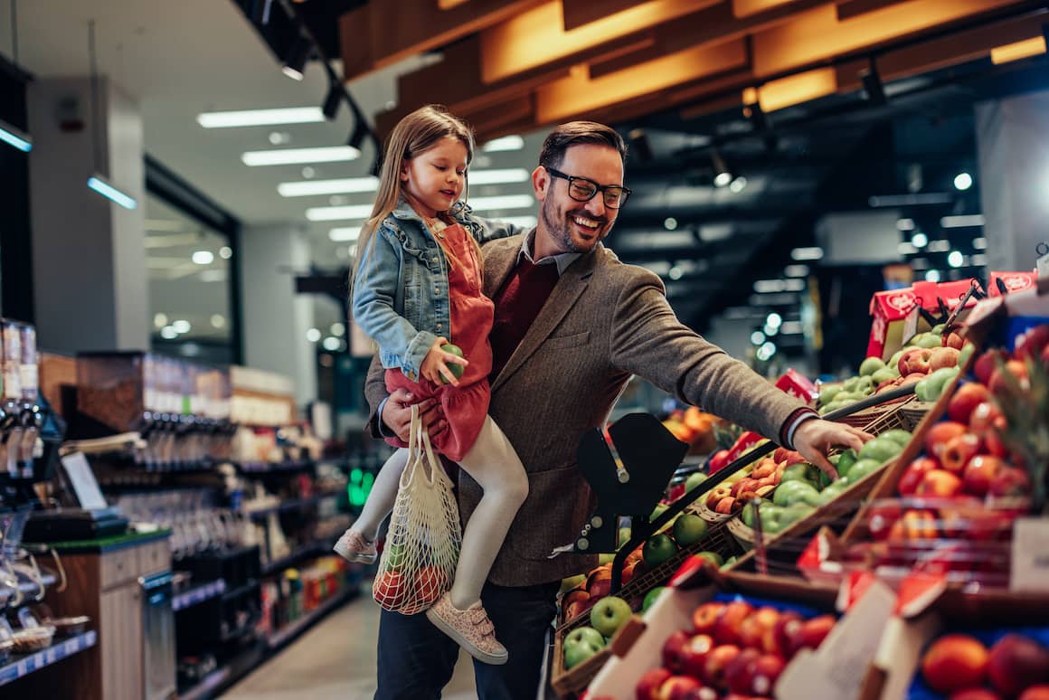 father with daughter grocery shopping and picking apples