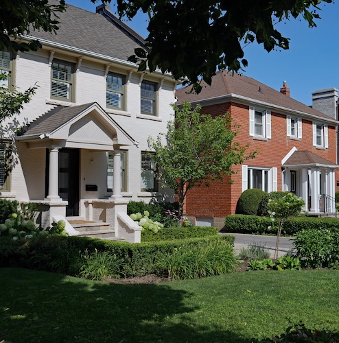 Row of detached houses with trees in the foreground.