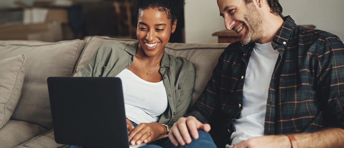 A smiling couple seated comfortably on a couch, expressing contentment.