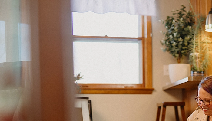 Woman petting two dogs on floor in kitchen.