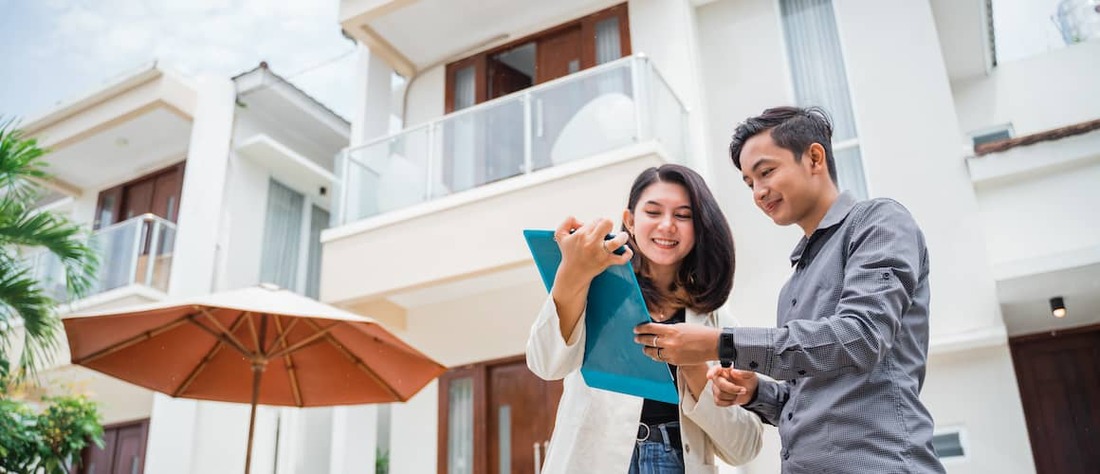 Real estate agent showing a man what's on her clipboard at an apartment complex.