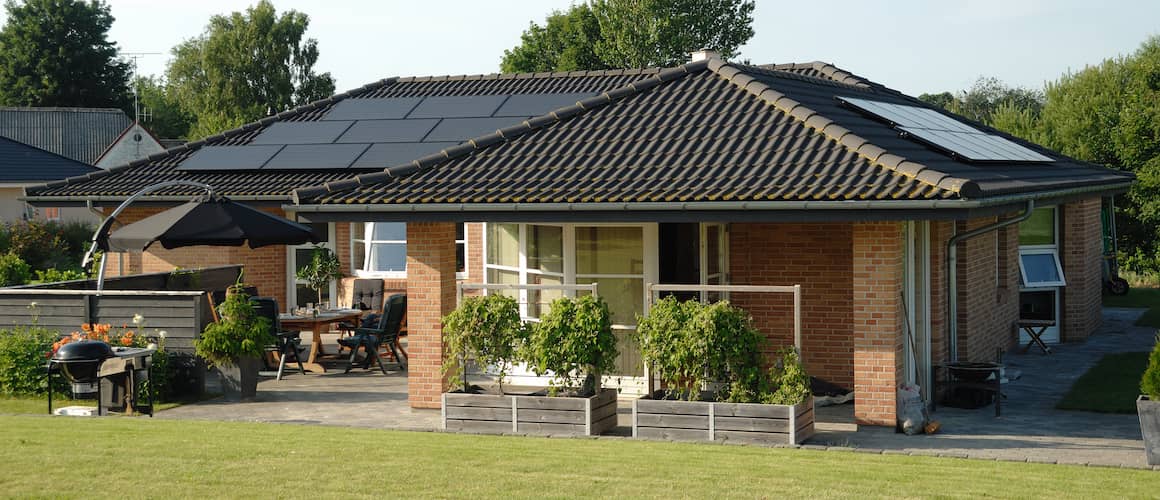 Brick ranch home with black gabled roof and solar panels.