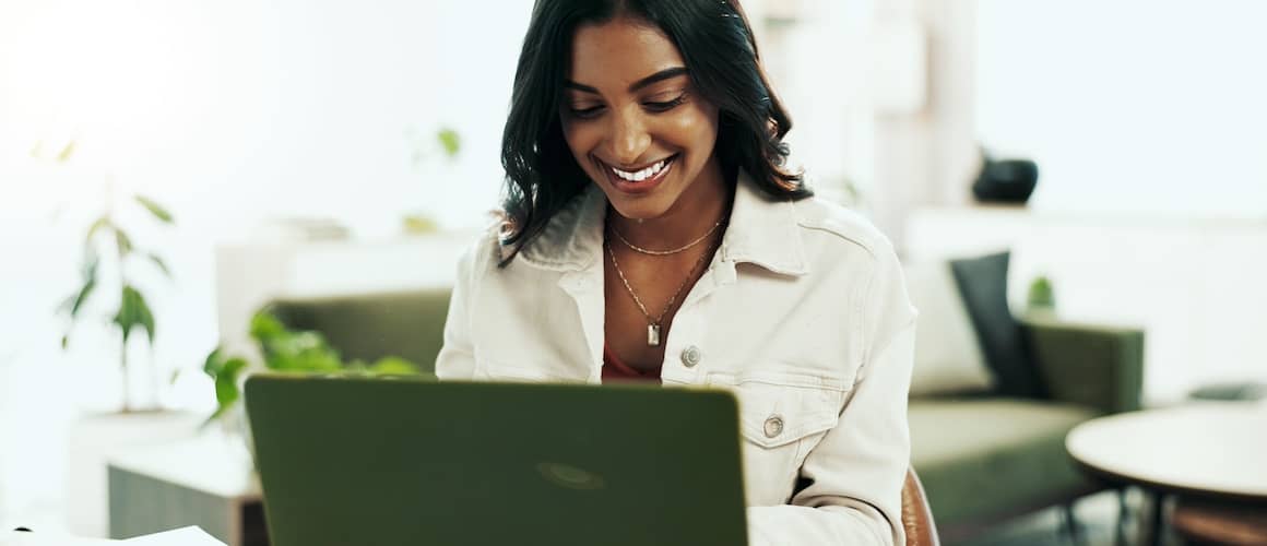 Smiling woman reading information on laptop.