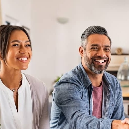 A couple sitting on a couch shaking hands, possibly symbolizing agreement or partnership in a home-related context.