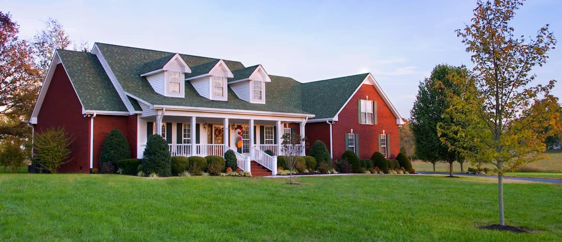 A large brick house in the countryside at dusk.