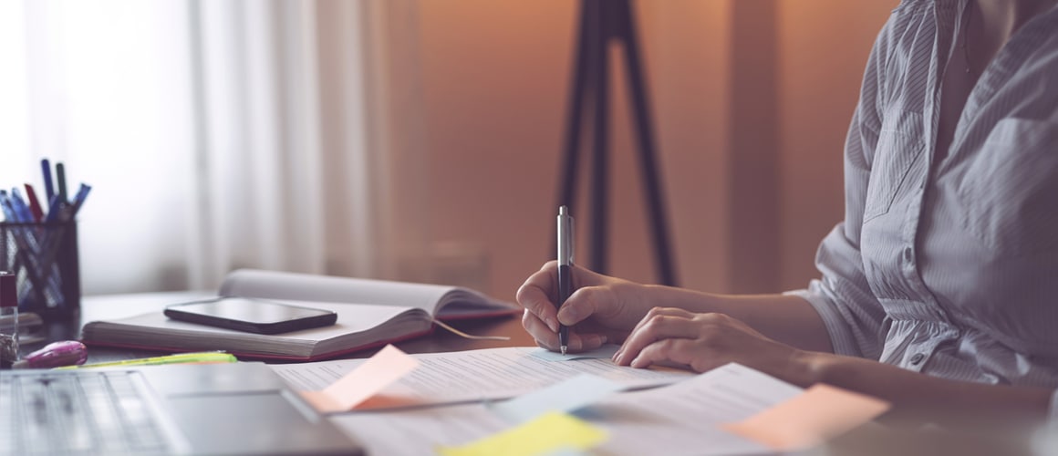 A woman writing something on paper possibly working on taxes or finance.