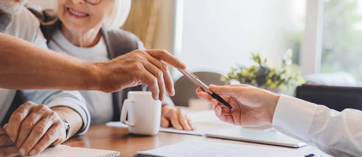 Older couple signing a home contract, potentially finalizing a property transaction.