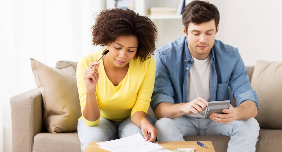 Young couple sitting on couch doing finances.