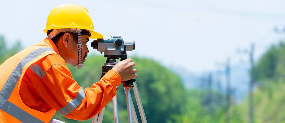 A land surveyor working in a field, illustrating a professional conducting a land survey.