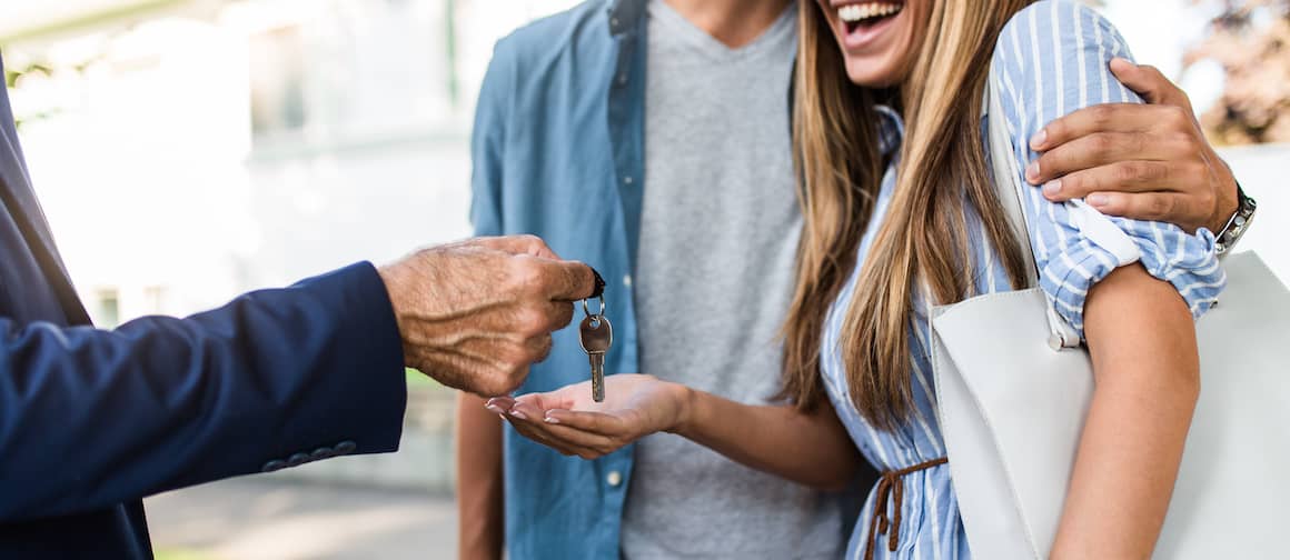 Agent handing keys to new home to home buyers.