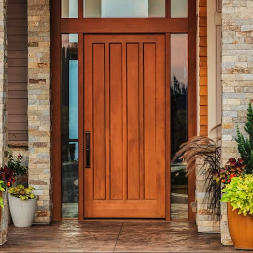 A front door with a large wooden door and potted plants, creating a warm and inviting entrance.