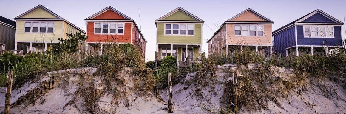 Beachfront homes, showcasing houses of different colors situated by the beach or ocean.