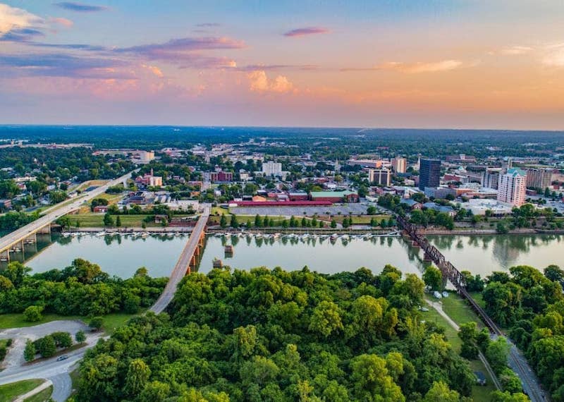 Aerial expansive view of towns in Richmond County Georgia featuring water, dense trees, and roadways stretching over the water toward city views.