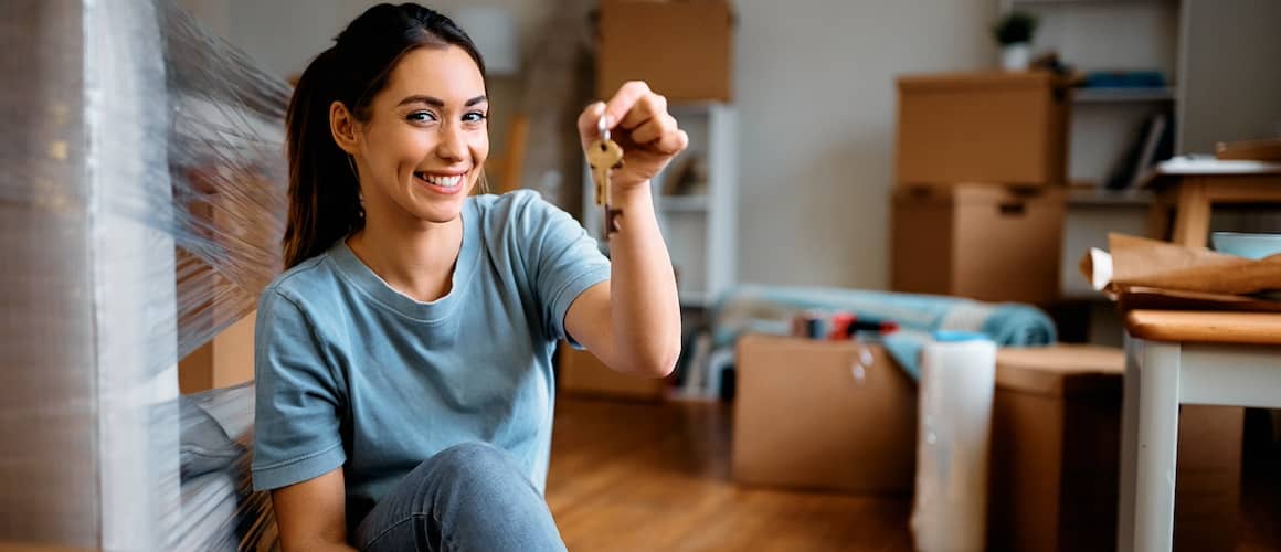 Young happy woman holds key while moving into new home