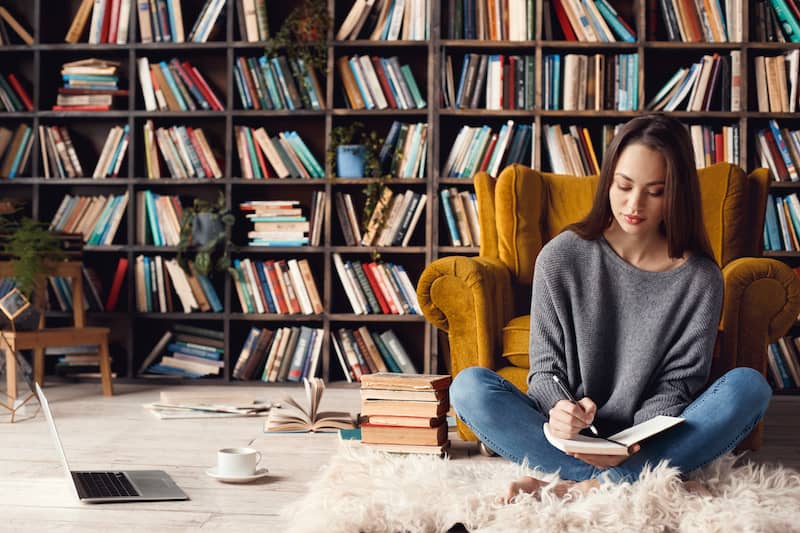 Woman sitting on floor of library with modular shelving.