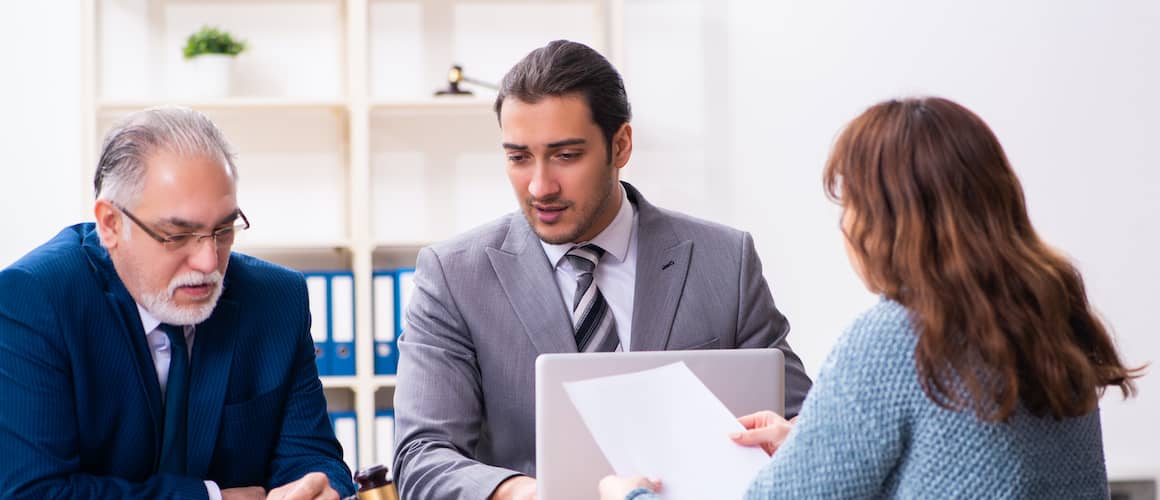 Two lawyers or real estate agents discussing some documents with a women.