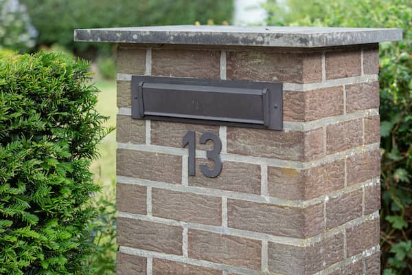 Square, brick mailbox labelled with the number 13.