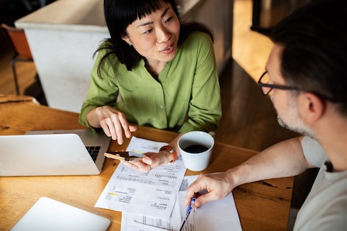 Couple looking over bills while drinking coffee.