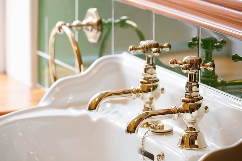 RHB Assets From IGX: Luxurious Art Deco bathroom with brass faucets and black marble.