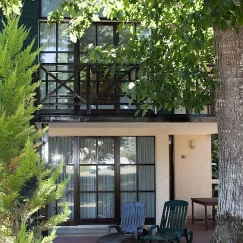 A charming house with a balcony and a tree in front, creating a serene and inviting atmosphere.