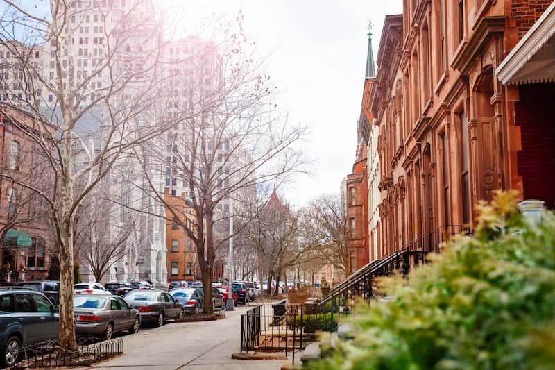 State Street in Albany near Emmanuel Baptist Church with a row of historic townhomes on one side and historic buildings and skyscrapers on the other side.