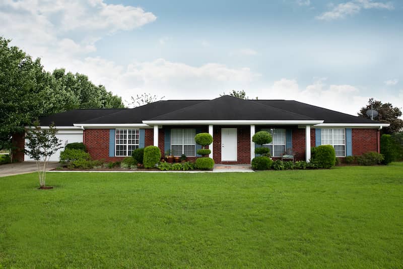 Brick ranch style home in the suburbs with a nice lush green lawn.