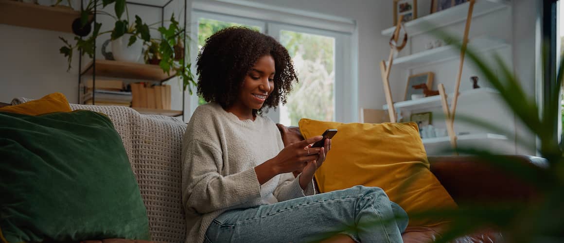 Woman on phone in living room, smiling.