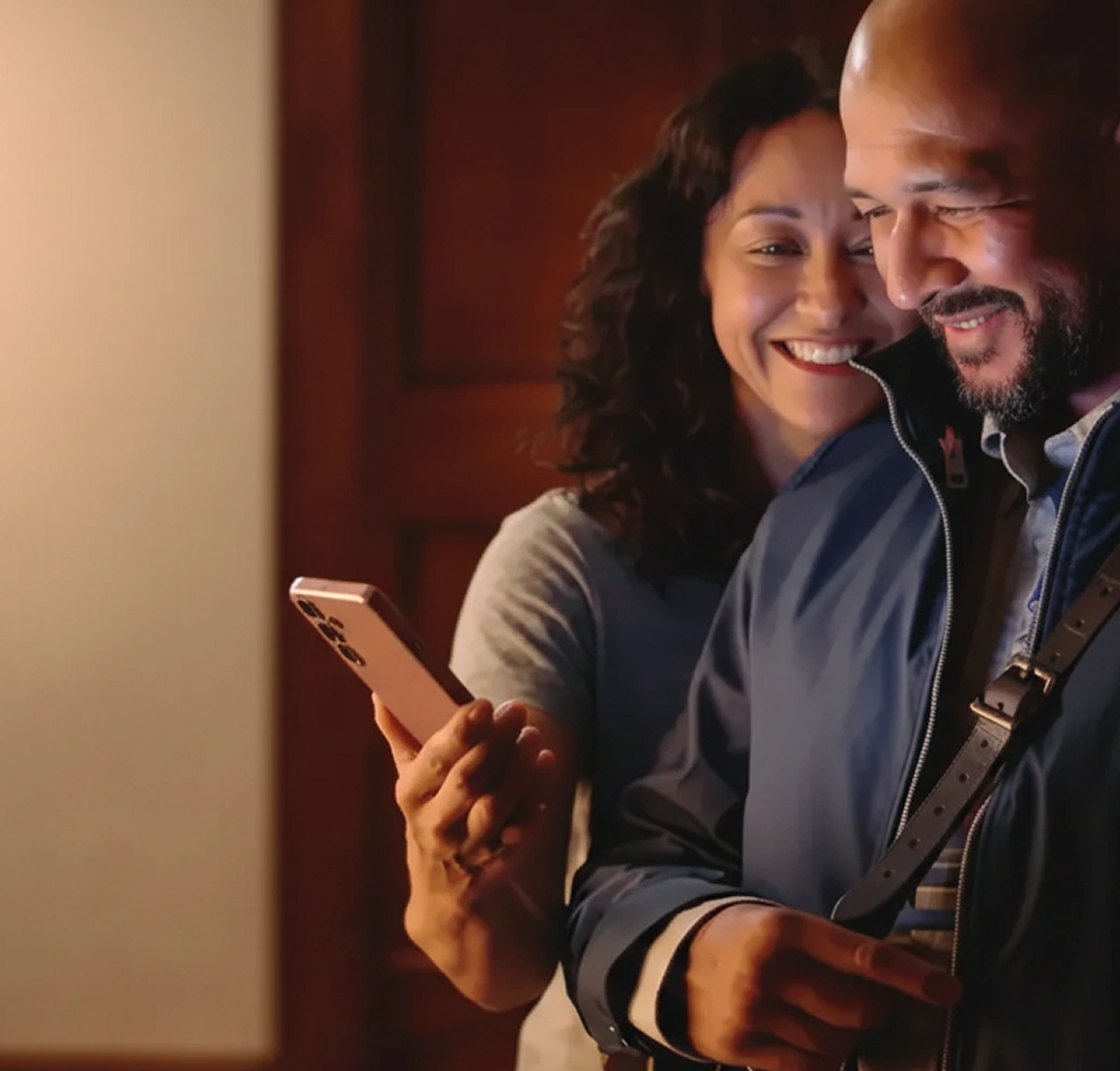 A woman showing a phone screen to her husband while standing close beside him.