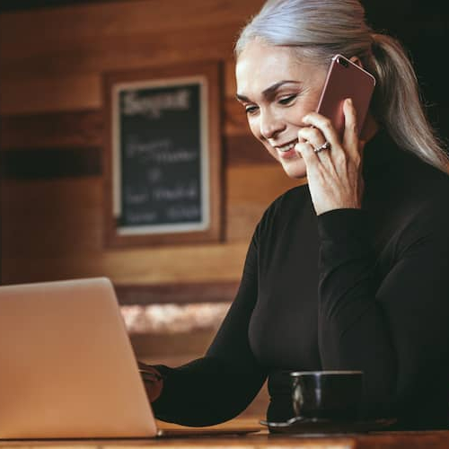 Businesswoman at a cafe making a phone call, potentially discussing business or financial matters.