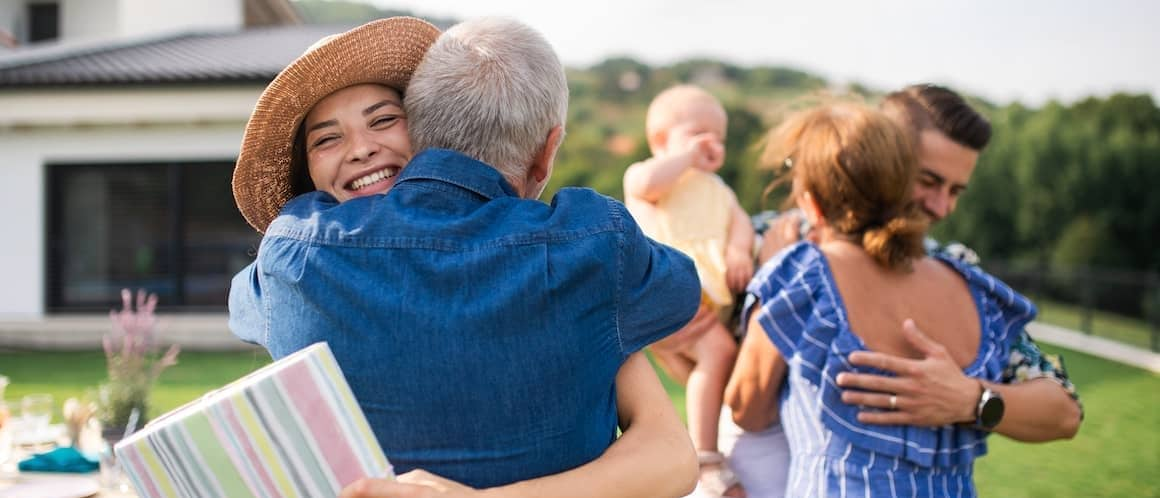 Parents hugging their daughter and son-in-law, depicting a family moment or celebration.