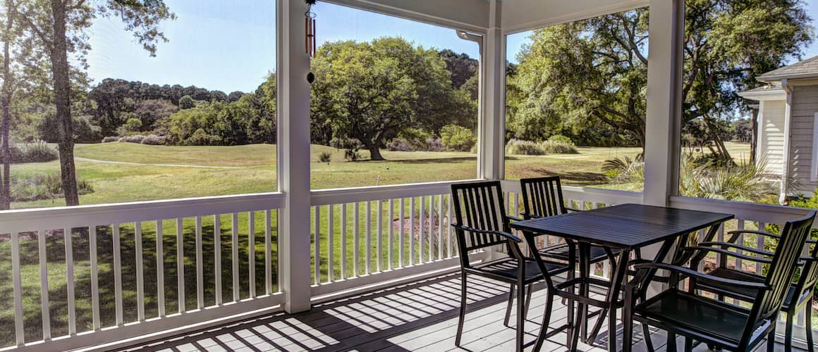 Screened porch with a table and chairs.