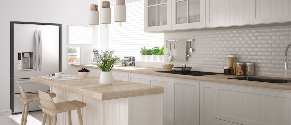 White minimalist kitchen with marble counters and stainless steel appliances.