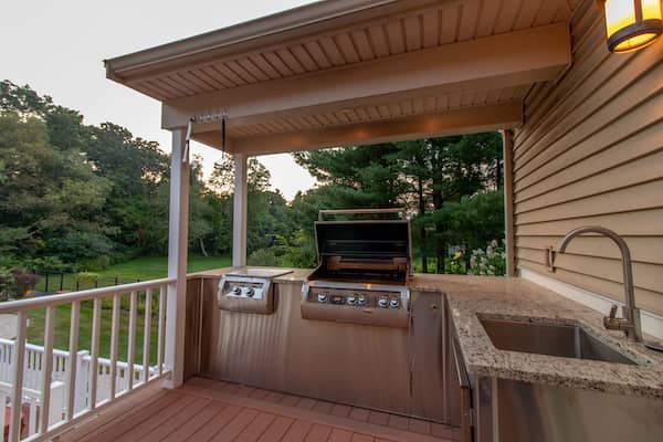 Outdoor kitchen attached to the back patio of a house.