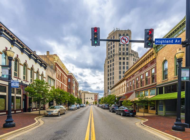 RHB Assets From IGX: Brick street lined with shops and a stoplight in a charming town.