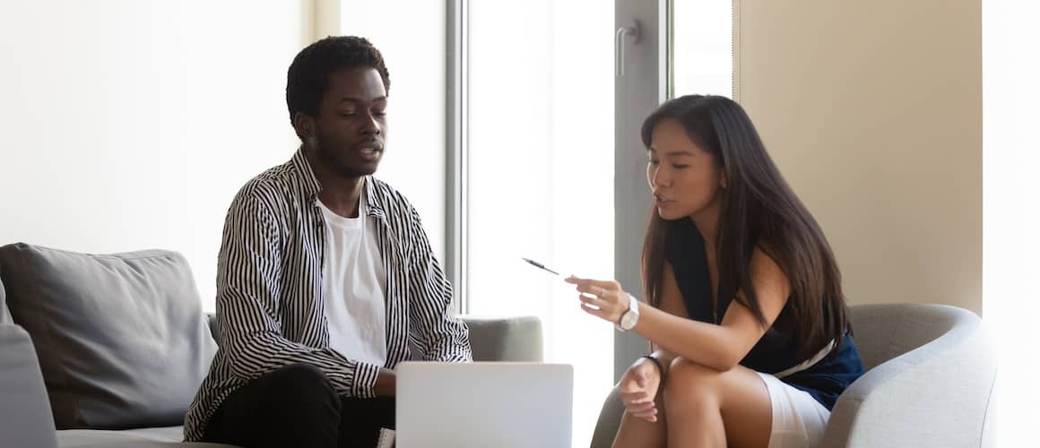 Man and woman colleagues sitting together discussing over a laptop.