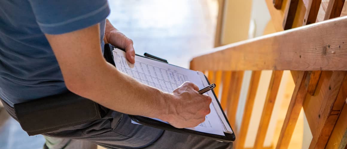 Image of home inspector investigating new house with clipboard.