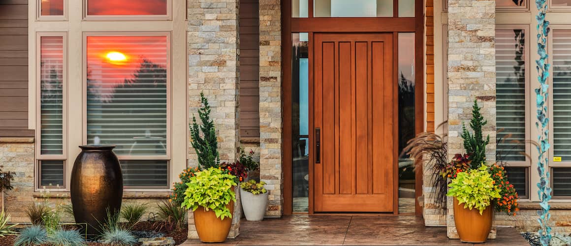 A front door with a large wooden door and potted plants, creating a warm and inviting entrance.