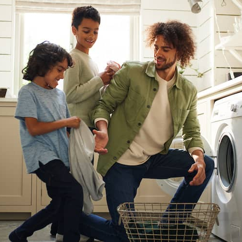A father doing laundry with his sons, representing family life or household activities.