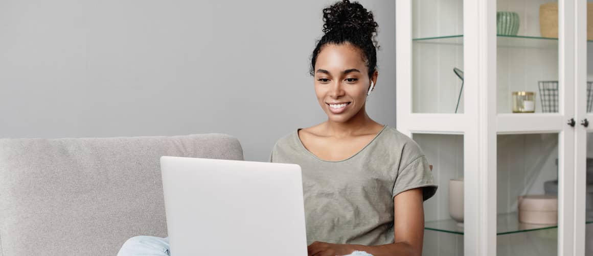 Young woman looks at laptop.