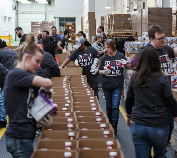 A group of Rocket employees volunteers at a food bank, loading food into boxes.