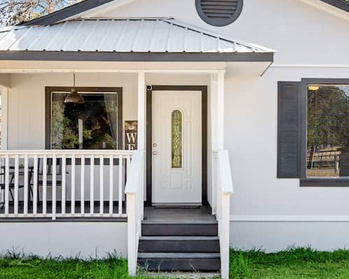 A small white one-story house with a neatly maintained front yard, depicting a cozy residential setting.