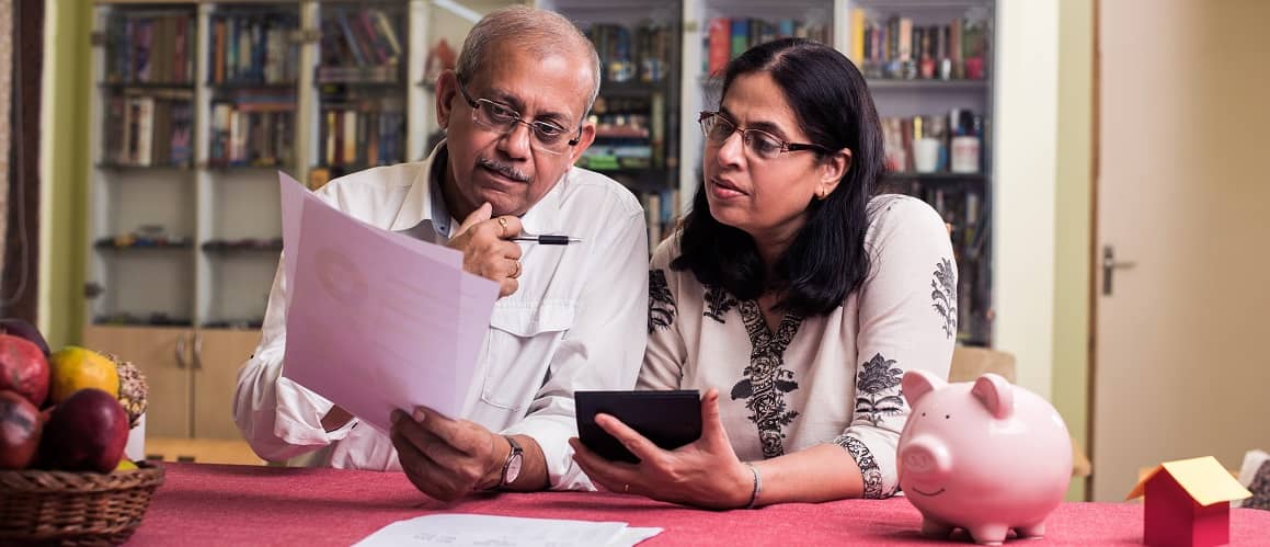 Older couple looking at papers together in their kitchen.