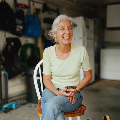 Woman smiling in garage chair holding horsehair brush.