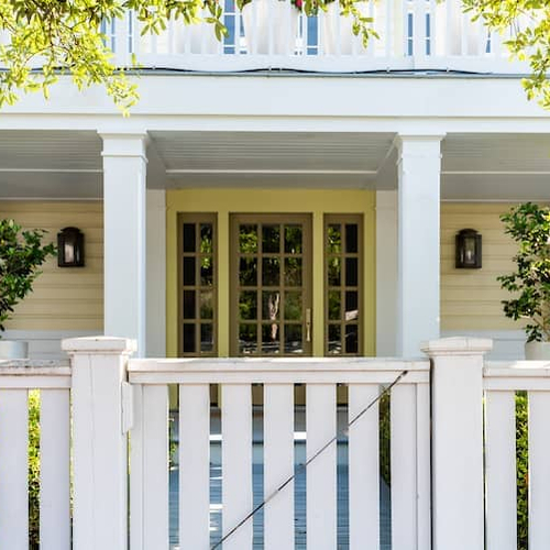 Wooden architecture of a house door leading to a front porch and yard with green landscaping, portraying a welcoming entrance.