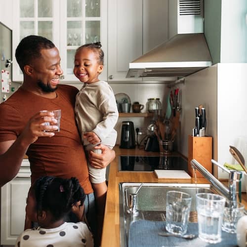 Dad and young daughters in kitchen.