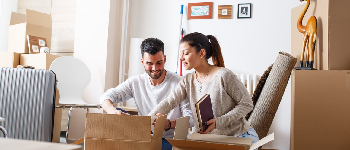 A man and women unboxing cardboard boxes after moving into the new residence.